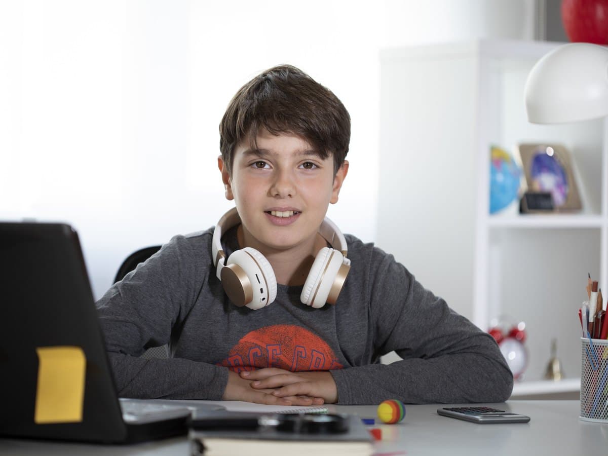 A Prep School pupil at his desk, headphones round his neck, waiting for the next lesson to begin